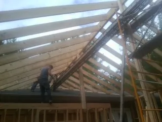 Rafters going up over a new addition with a worker on the wall in Glendale